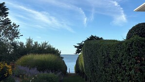Un sentiero nel giardino conduce a specchio d'acqua, circondato da siepi curate e arbusti diversi.