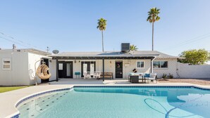 Una propiedad residencial con piscina, mobiliario exterior y palmeras.