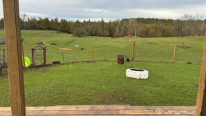 Eine Wiese mit einer Holzterrasse, einer kleinen Konstruktion und einem Zaun.