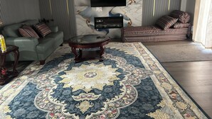 Ein Wohnzimmer mit einer Couch, einem Couchtisch, einem Fernseher und einem gemusterten Teppich.