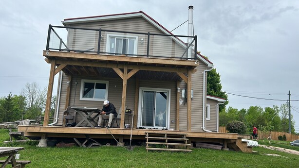 Ein zweistöckiges Haus mit Balkon, Schornstein und einer Holzterrasse.