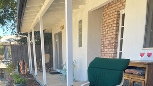 Een terras buiten, met een barbecue, zithoek en een bakstenen muur.