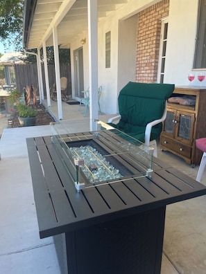 An outdoor patio with a barbecue grill, seating area, and a brick wall.