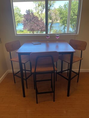 Una mesa de comedor con cuatro sillas, dos copas de vino y un libro sobre la mesa.