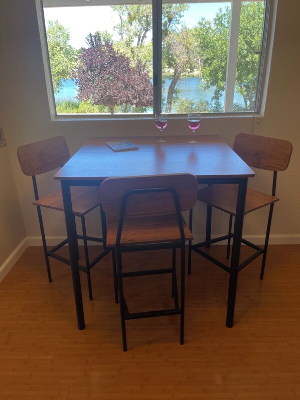 A dining table with four chairs, two wine glasses, and a book on the table.