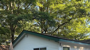 Ein eingeschossiges Haus mit einer Terrasse, einer überdachten Veranda und einem kleinen Garten.