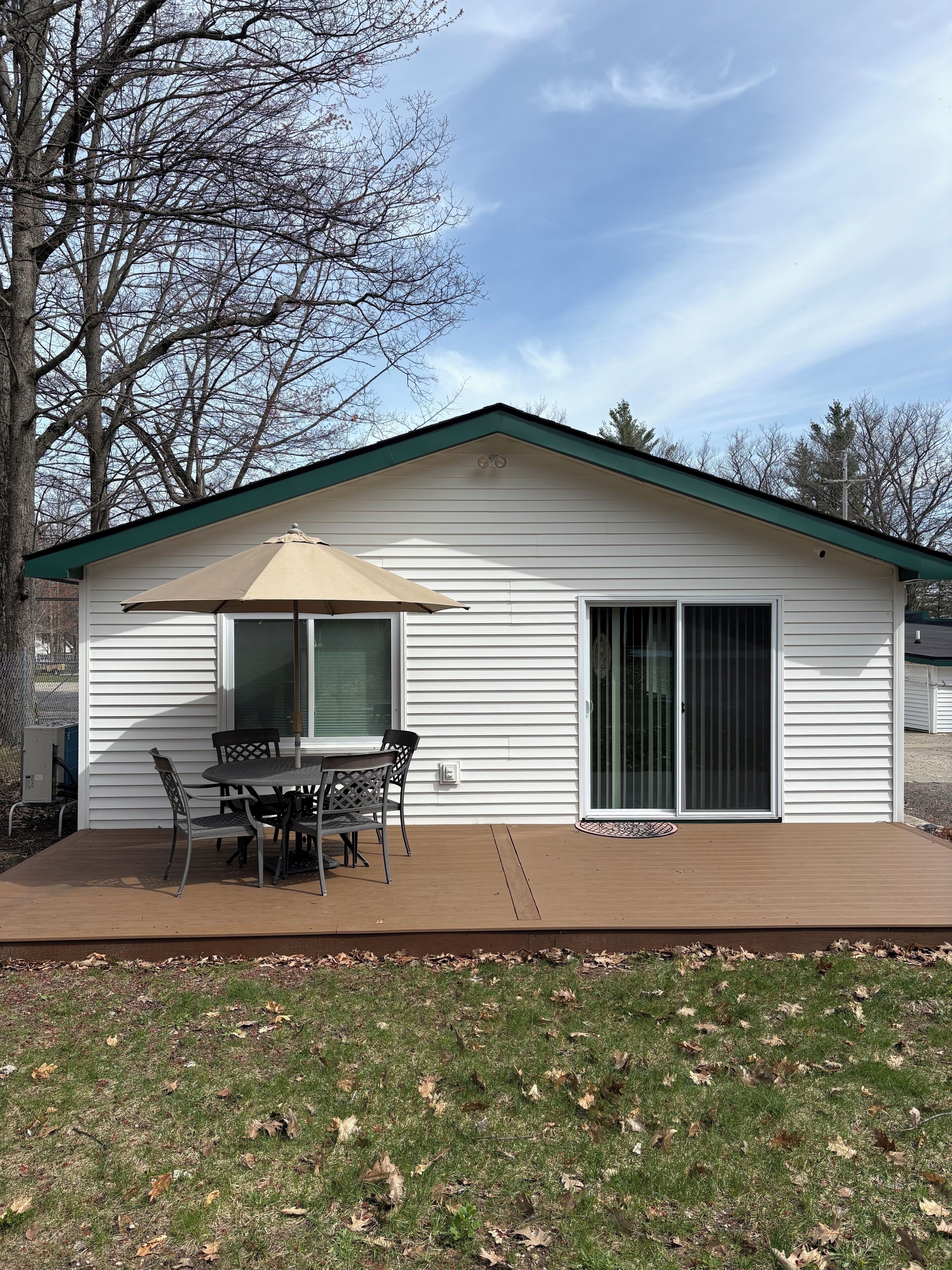 Une maison de plain-pied avec un patio, une table et des chaises, et une grande porte-fenêtre coulissante.