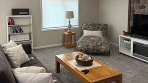 Ein Wohnzimmer mit einer Couch, einem Couchtisch, einem Bücherregal, einer TV-Konsole und einem Wandzeichen mit der Aufschrift 'HIGGINS LAKE'.