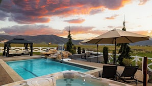A swimming pool with hot tubs, outdoor seating, and a view of mountains. - Ultimate Family Retreat: VIEWS, Sport Court, Theater, Pool, Sauna, Game Zone! (Heber City)