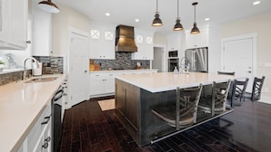A modern kitchen with a large island, stainless steel appliances, and pendant lighting. - Ultimate Family Retreat: VIEWS, Sport Court, Theater, Pool, Sauna, Game Zone! (Heber City)