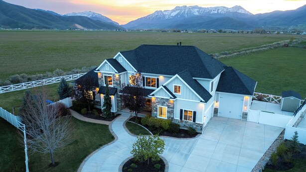 A large, two-story house with a stone facade, a dark roof, and a well-maintained lawn. - Ultimate Family Retreat: VIEWS, Sport Court, Theater, Pool, Sauna, Game Zone! (Heber City)