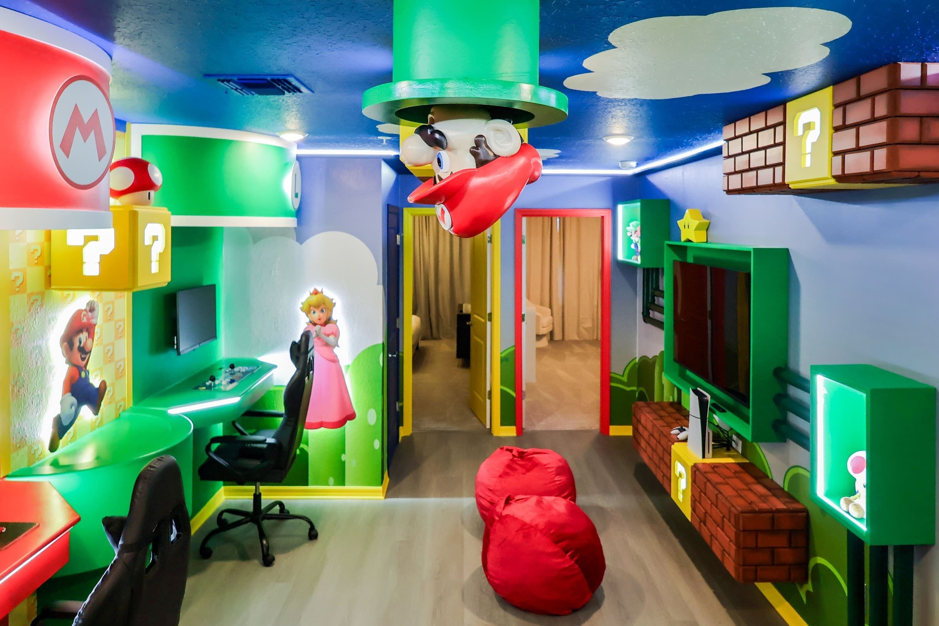 A colorful room with a Mario-themed desk, a red bean bag, and a television.