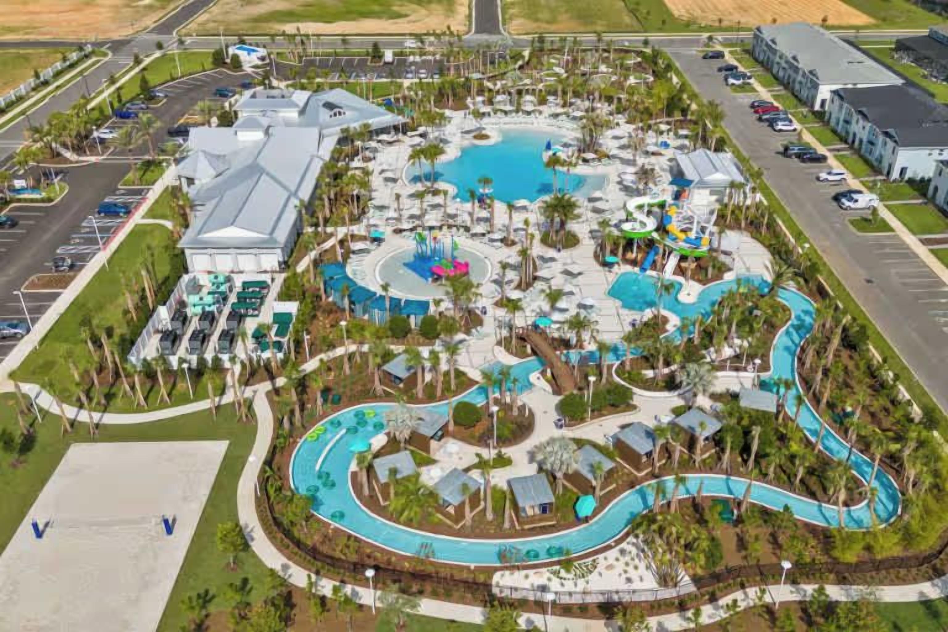 An aerial view of a resort with a central pool, multiple water slides, and a parking lot.