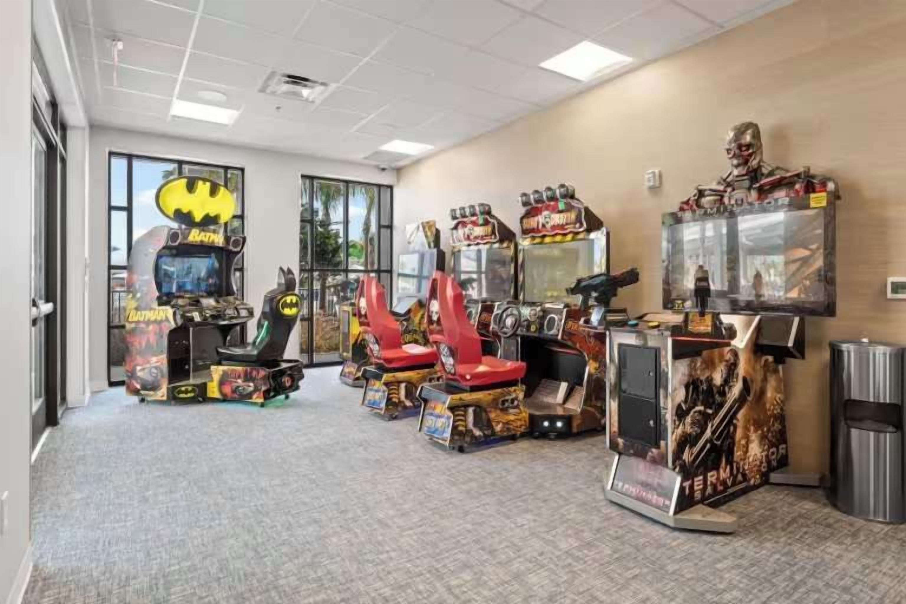 A room with arcade machines, a Batman-themed machine, and a Terminator poster.