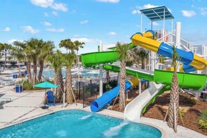A pool area with a water slide, palm trees, and lounge chairs. - Modern 5BR Home with Game Room and Pool at Windsor Cay Resort (Clermont)