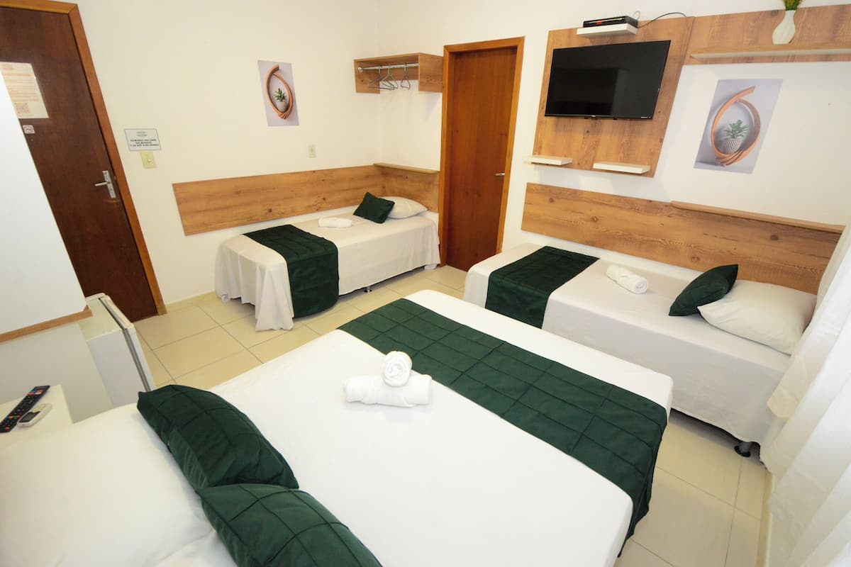 A hotel room with two single beds, a TV, and a wooden headboard.