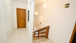 Un couloir avec une porte en bois, un escalier et un panneau sur le mur.