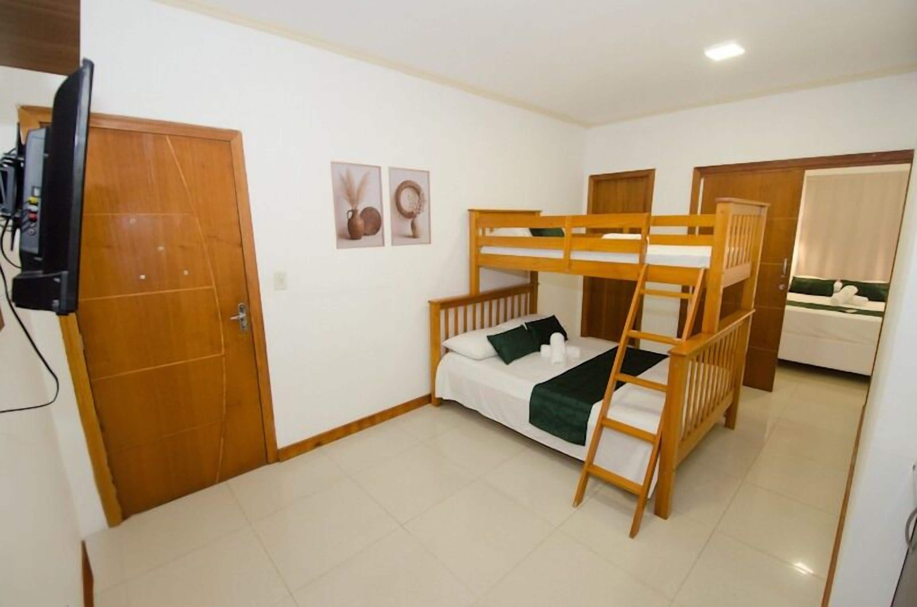 A bunk bed room with a television, wooden doors, and a small bathroom.