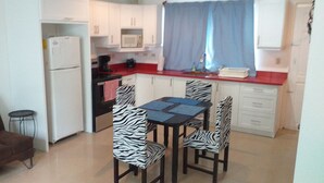 A compact kitchen with white cabinets, a red countertop, a zebra-striped table, and a brown sofa with a pillow. - Cozy 2-bedroom apartment in charming Tamarindo with AC (Tamarindo)