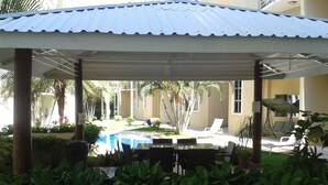 A covered outdoor area with a pool, lounge chairs, and potted plants. - Cozy 2-bedroom apartment in charming Tamarindo with AC (Tamarindo)