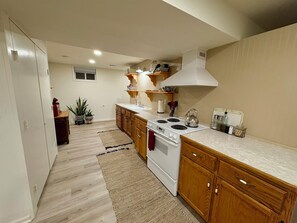 A kitchen with wooden cabinets, a white stove, and a countertop. - Peaceful Home Base For World Cup Stay Sleeps 6+ (Tonganoxie)