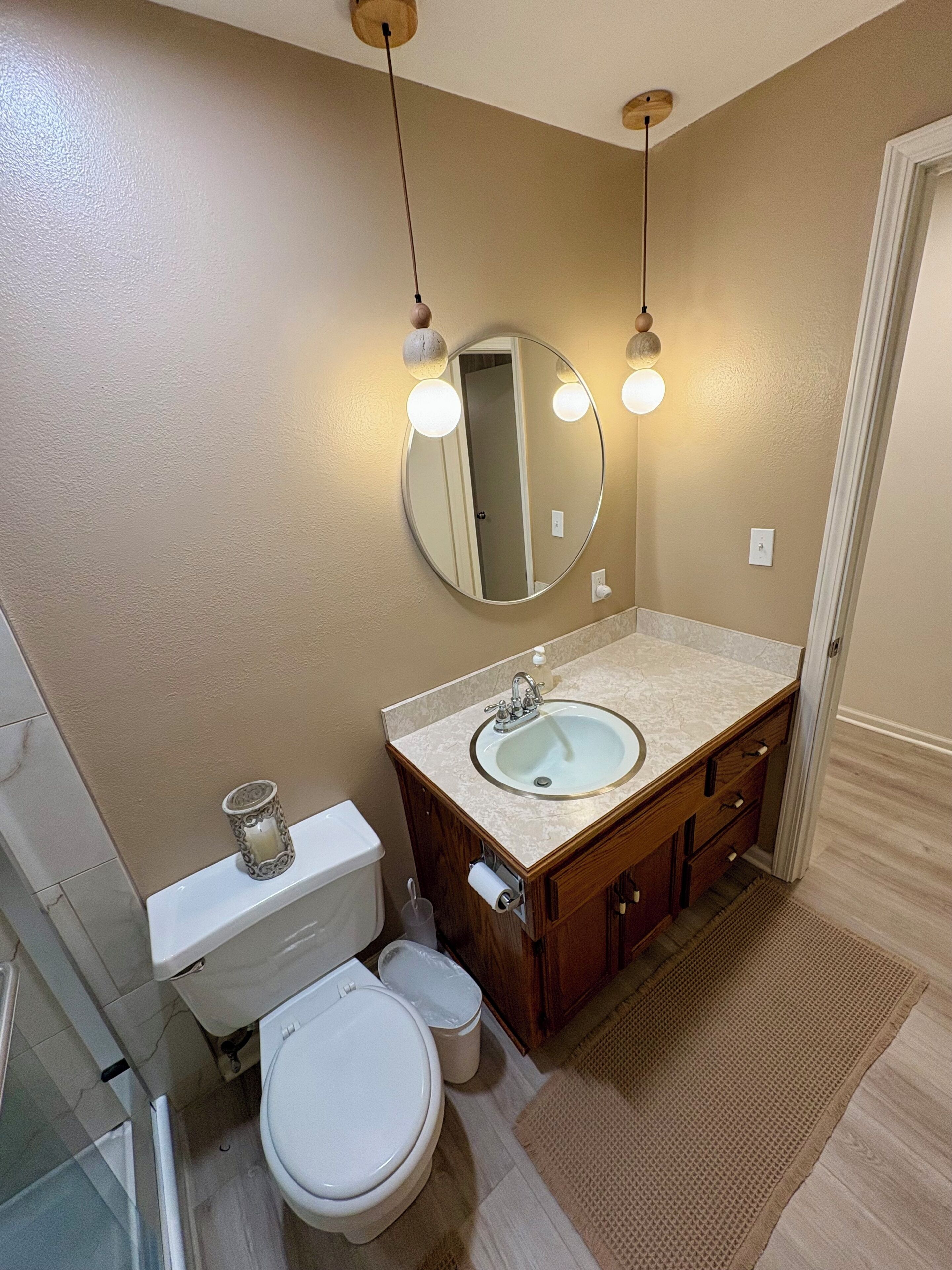 A bathroom with a toilet, sink, mirror, and wooden cabinets.