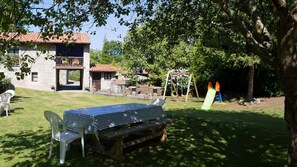 A backyard with a table and chairs, a swing set, and a slide. - Sotu Mill (Colunga)