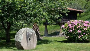 Un monumento de piedra, una edificación tradicional y flores rosadas en un jardín.
