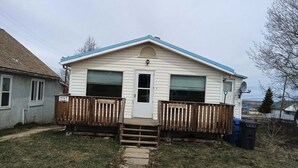 A single-story house with a front porch, a small front yard, and a satellite dish.