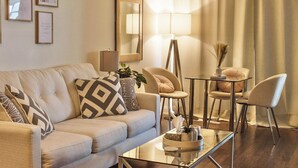 A living room with a sofa, two chairs, a glass coffee table, a floor lamp, and a mirror. - Upscale Toronto Condo | Monthly Stay (Toronto)