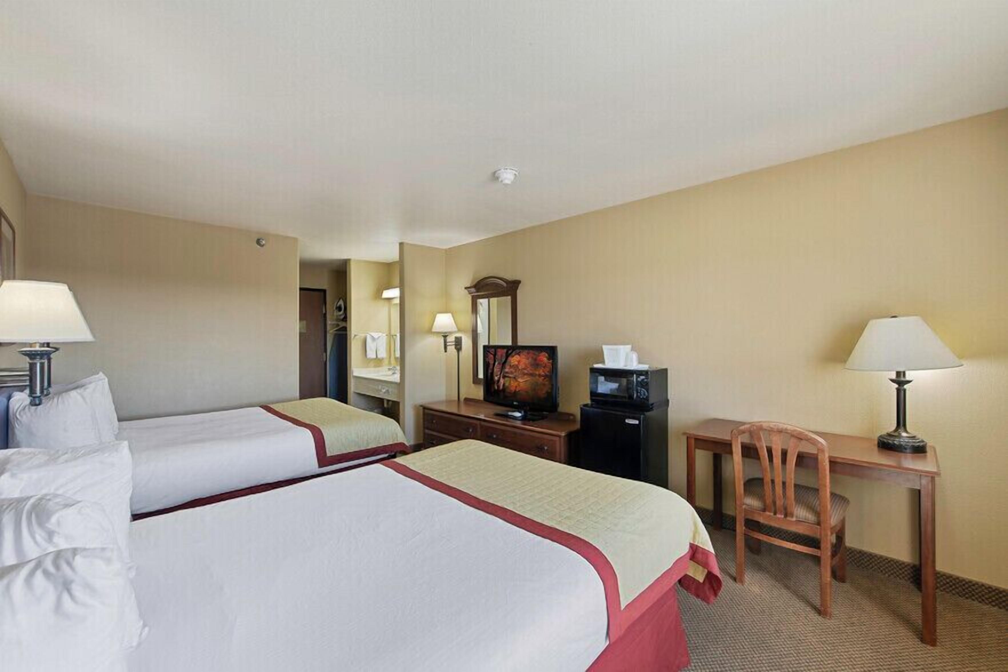 Habitación de hotel con dos camas, televisión, escritorio y una silla.