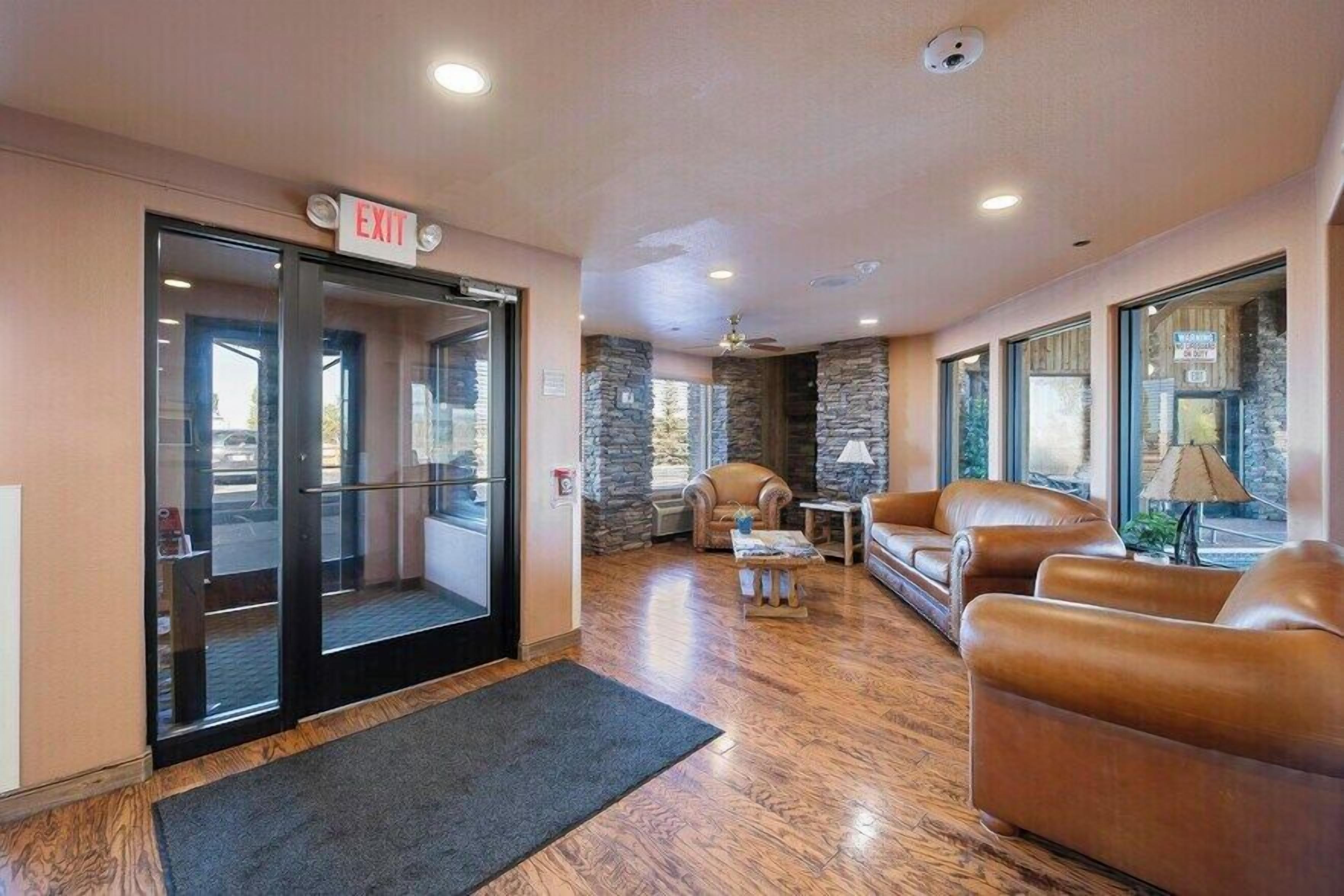 A lobby with an exit sign, stone walls, leather sofas, a coffee table, and a lamp.