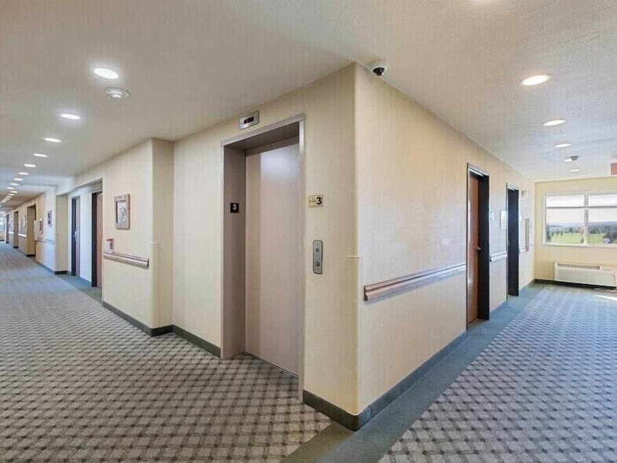 A hotel corridor with a patterned carpet, beige walls, and doors numbered 3 and 4.
