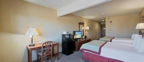 Ein Hotelzimmer mit Schreibtisch, zwei Betten, Fernseher und Spiegel.