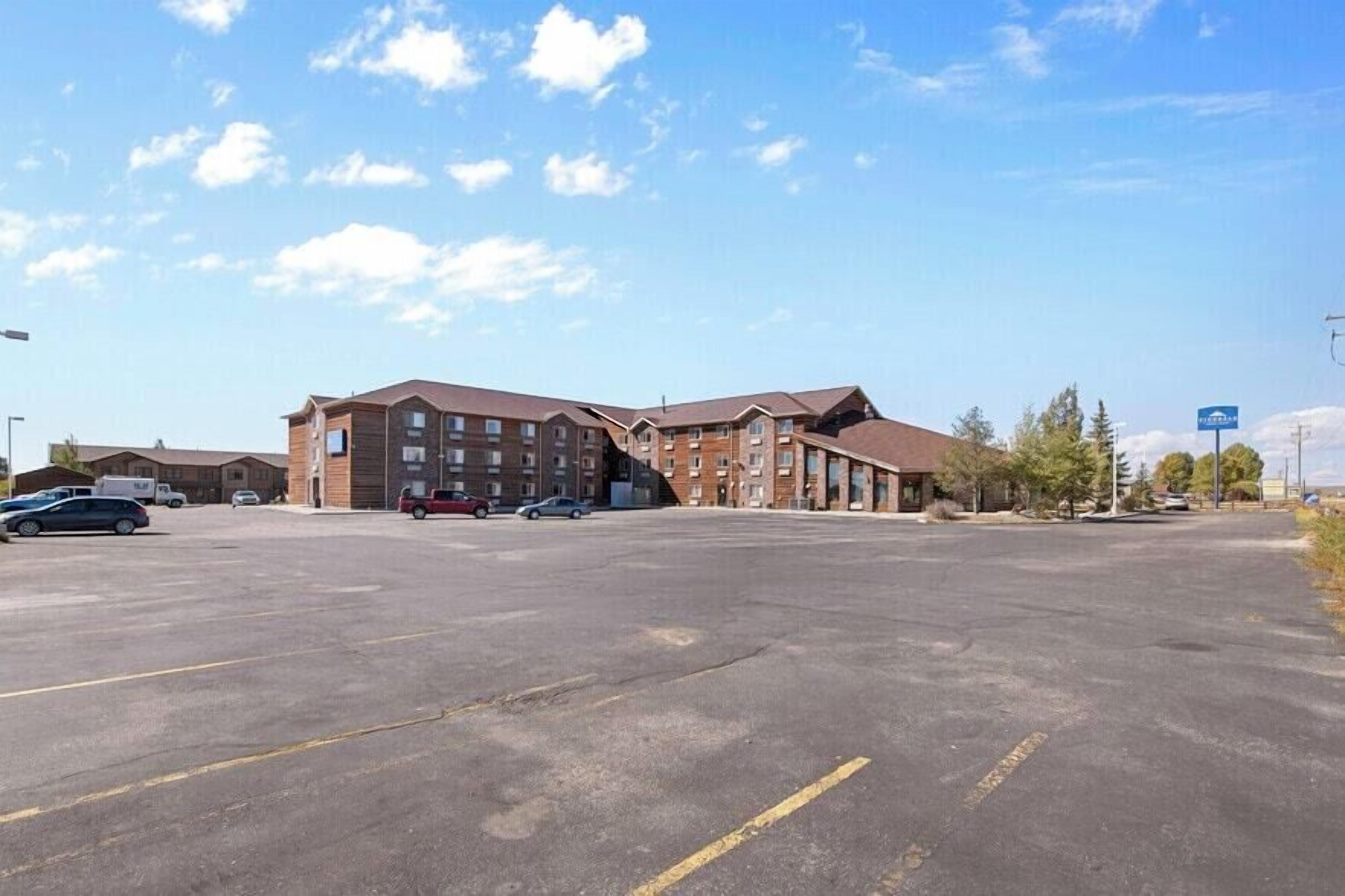 A multi-story hotel with a parking lot in front.