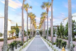 A pathway lined with palm trees and buildings, suggesting a resort or hotel setting. - 30A Bachelorette House by Stay on 30a (Seacrest Beach)