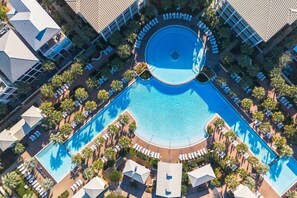 An aerial view of a hotel with a central swimming pool, surrounded by lounge areas and palm trees. - 30A Bachelorette House by Stay on 30a (Seacrest Beach)