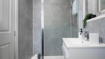 A modern bathroom with a glass shower enclosure, a white sink, and a mirror above it.