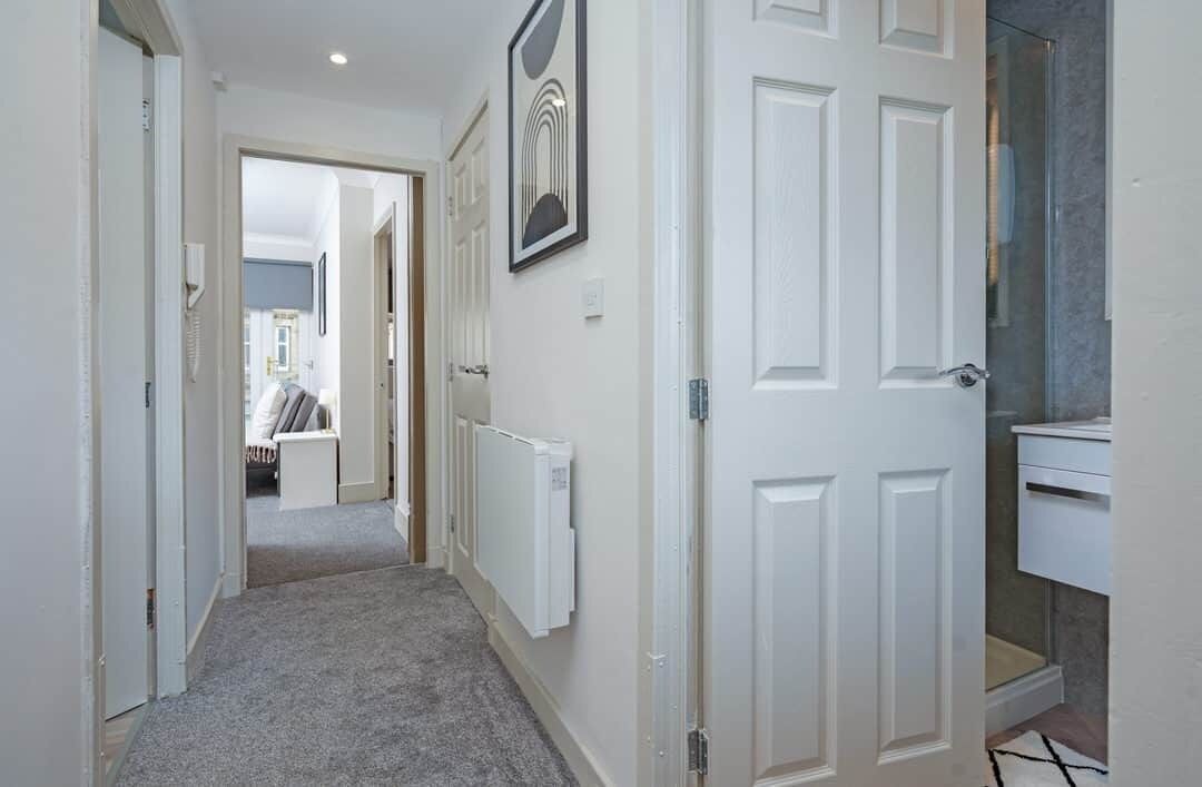 A hallway with white doors, a radiator, and a framed picture on the wall.