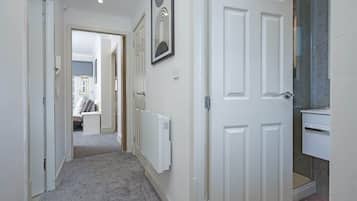 A hallway with white doors, a radiator, and a framed picture on the wall.