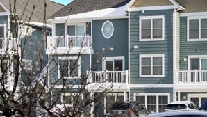 A multi-story residential building with a balcony, a garage, and a street sign indicating 'Hope St.' - Bayfront TC Condo · Walk to Beach & Downtown · Free Parking · Sleeps 6 (Traverse City)