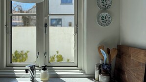 Una cocina con ventana, un lavabo, un grifo, dispensador de jabón y un portalapices.