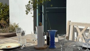 Mesa de madera al aire libre con platos, cubiertos y cristalería.