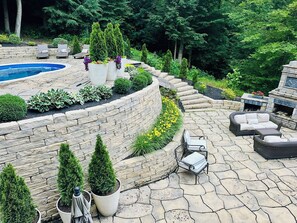 Ein angelegter Außenbereich mit Pool, Steintreppe und Gartenmöbeln.