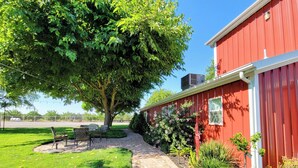 Un bâtiment rouge avec un chemin en briques menant à un espace aménagé avec des chaises et une table.