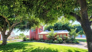 Un bâtiment rouge avec un toit blanc, entouré d’une végétation luxuriante et d’arbres.