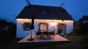 Uma casa com varanda, molduras de janela em pedra e luminária em formato de estrela.