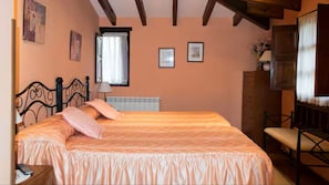 Une chambre à coucher comprenant un lit, une chaise, une table de chevet, un radiateur et une fenêtre avec des rideaux.