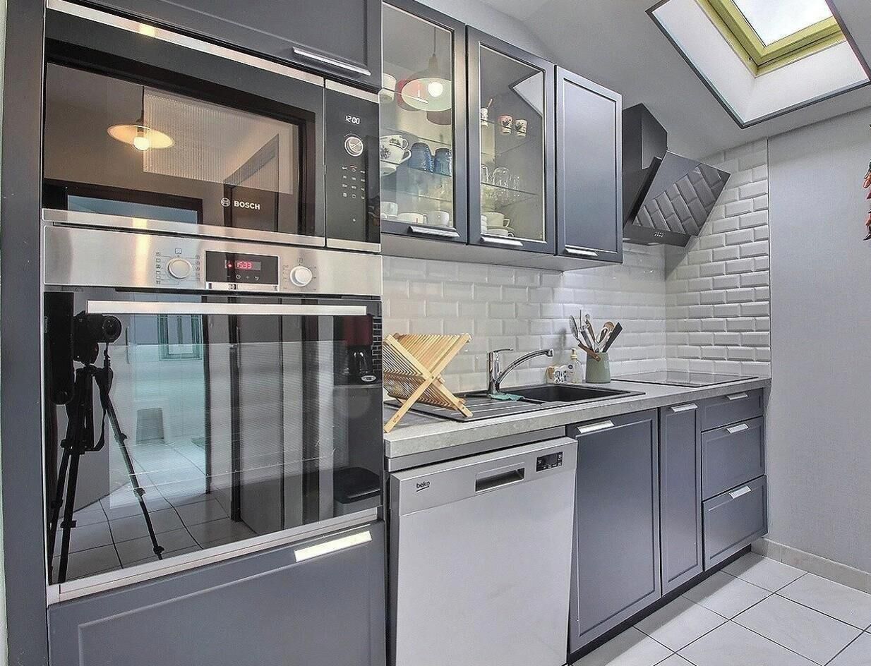 Una cocina moderna con horno Bosch, lavavajillas y un fregadero con un escurreplatos de madera.