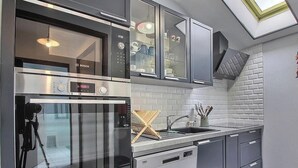 Een moderne keuken met een Bosch oven, een vaatwasser en een spoelbak met een houten afdruiprek.